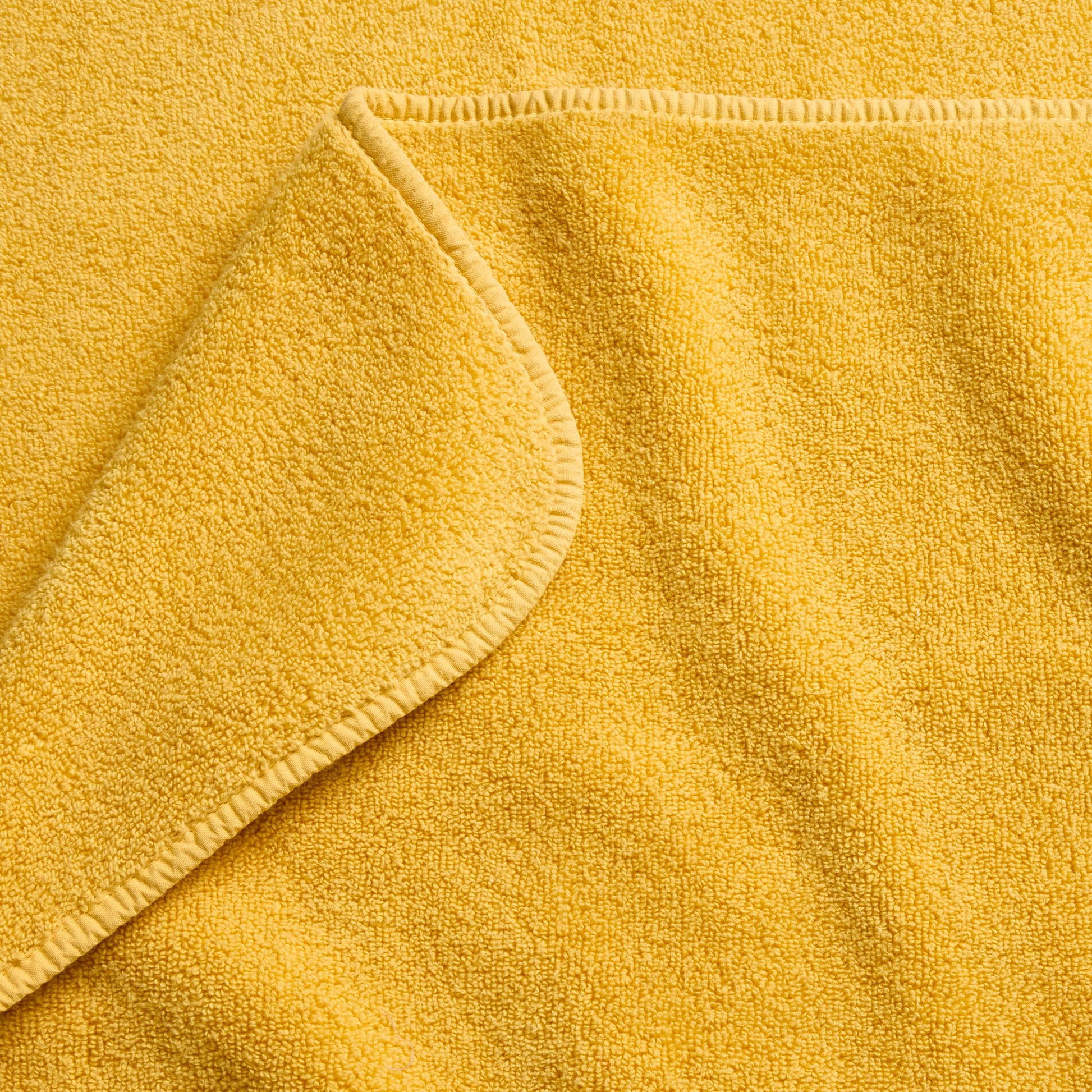 Bright yellow cotton bath towel with a soft, absorbent terry cloth texture and finished stitched edges.
