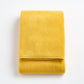 Folded bright yellow Signature bath towel made of soft, plush cotton terry fabric on a white background.