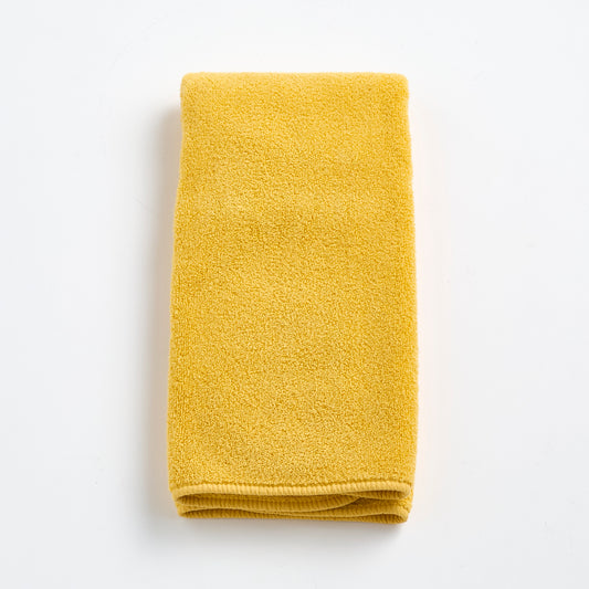 Folded bright yellow Signature hand towel made of soft, textured cotton fabric on a white background.