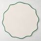 16-inch round off-white woven nylon placemat with a scalloped edge and pine green piped border.