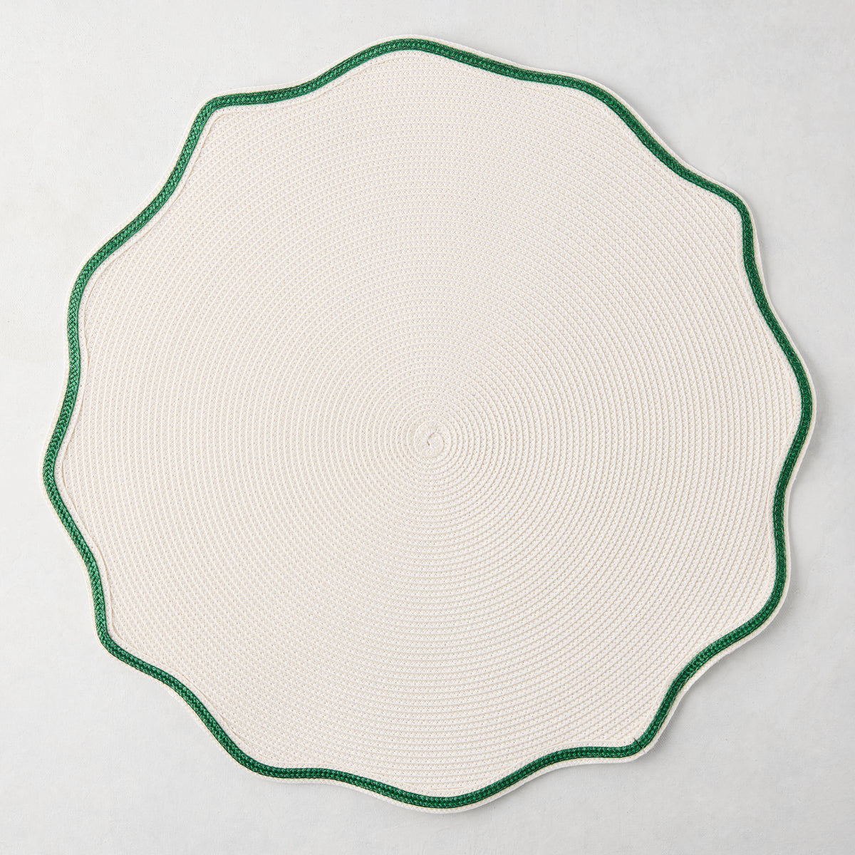 16-inch round off-white woven nylon placemat with a scalloped edge and pine green piped border.