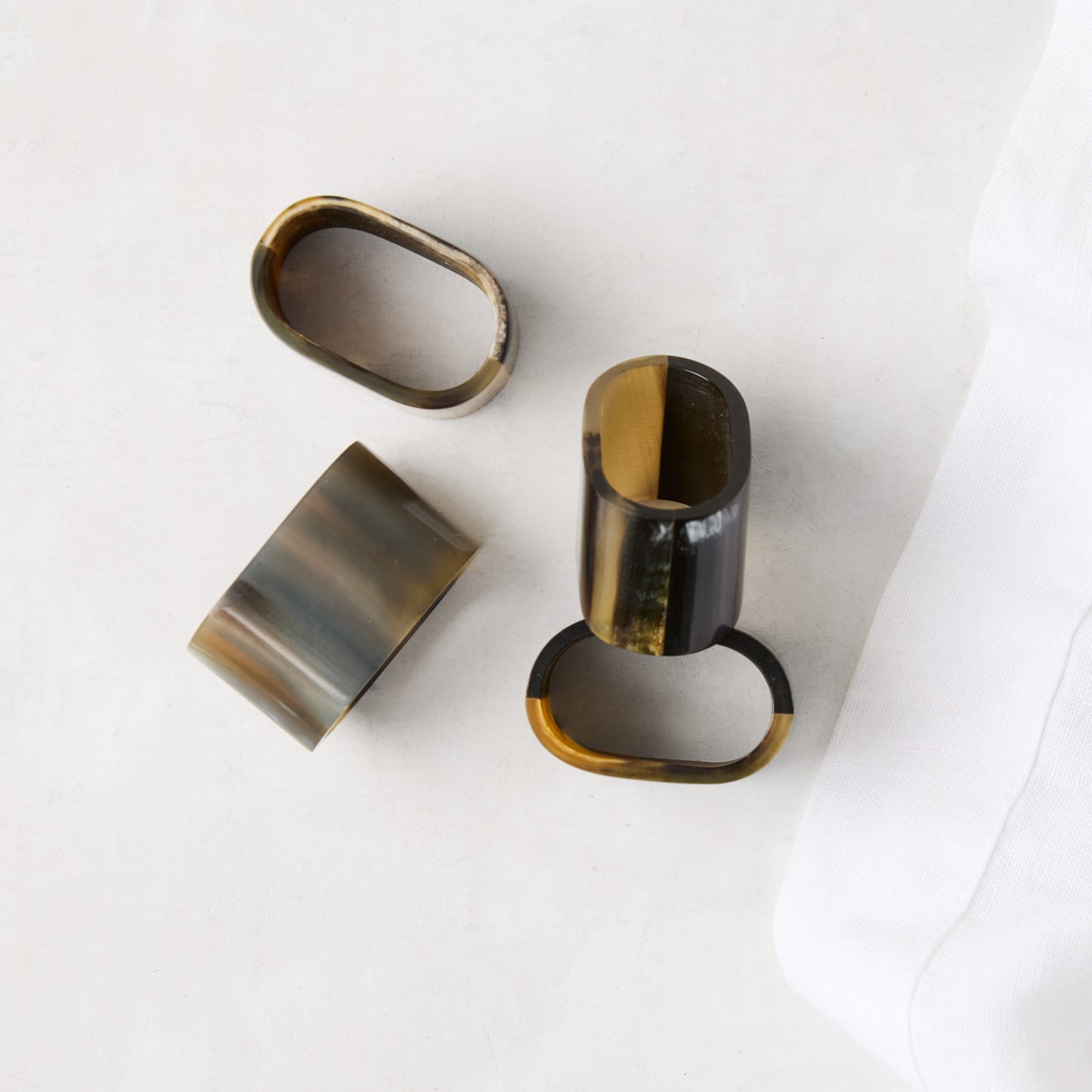 Set of 4 Horn Napkin Rings with unique natural variations in brown, black, and tan, on a white surface.
