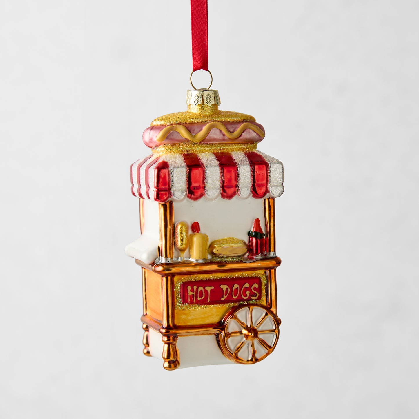 4-inch glass hot dog stand Christmas ornament with red and white striped awning, glitter accents, and red ribbon hanger.