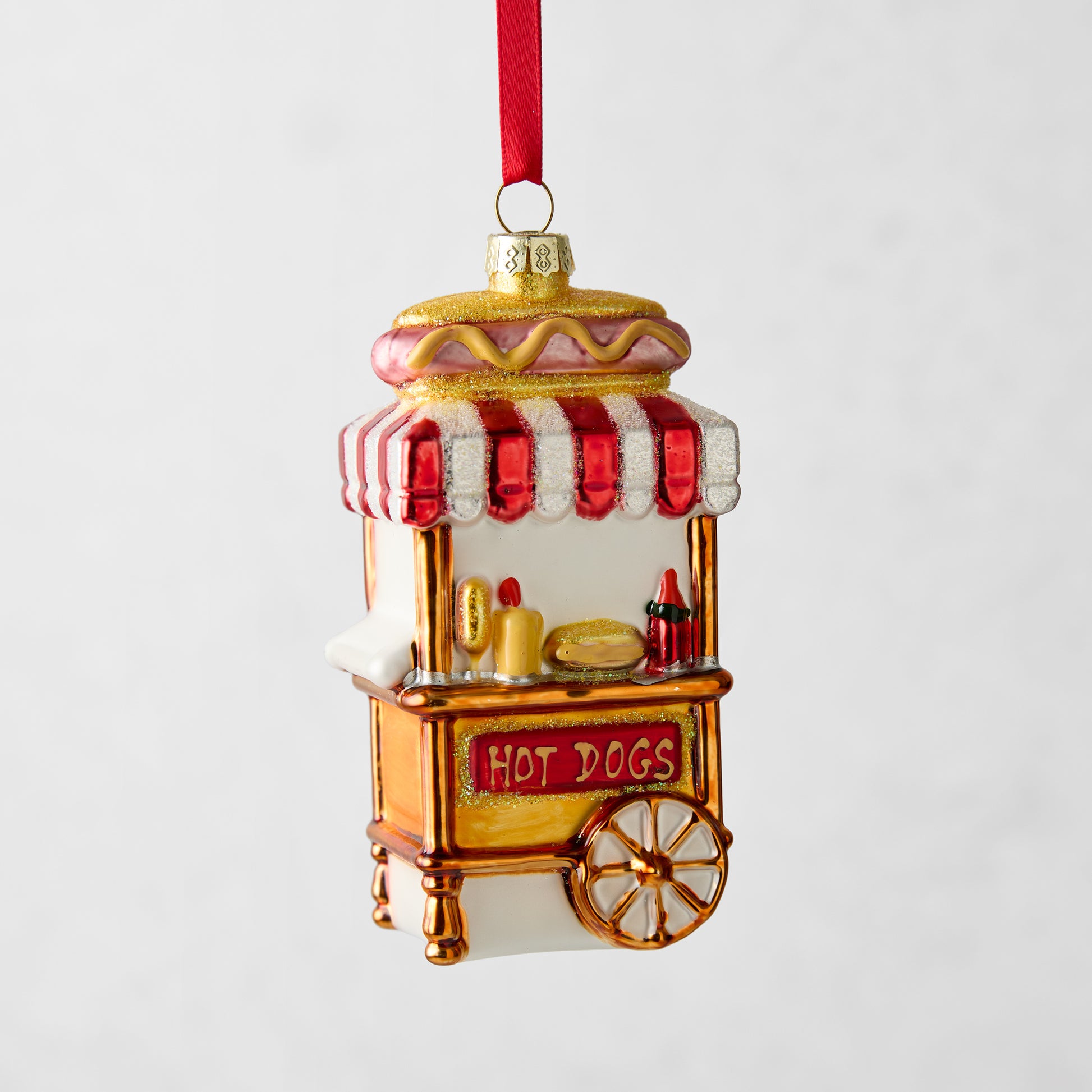 4-inch glass hot dog stand Christmas ornament with red and white striped awning, glitter accents, and red ribbon hanger.
