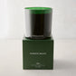 Hudson Grace Aspen 3-wick candle in a dark green glass vessel, atop a matching green gift box.