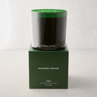 Hudson Grace Aspen 3-wick candle in a dark green glass vessel, atop a matching green gift box.
