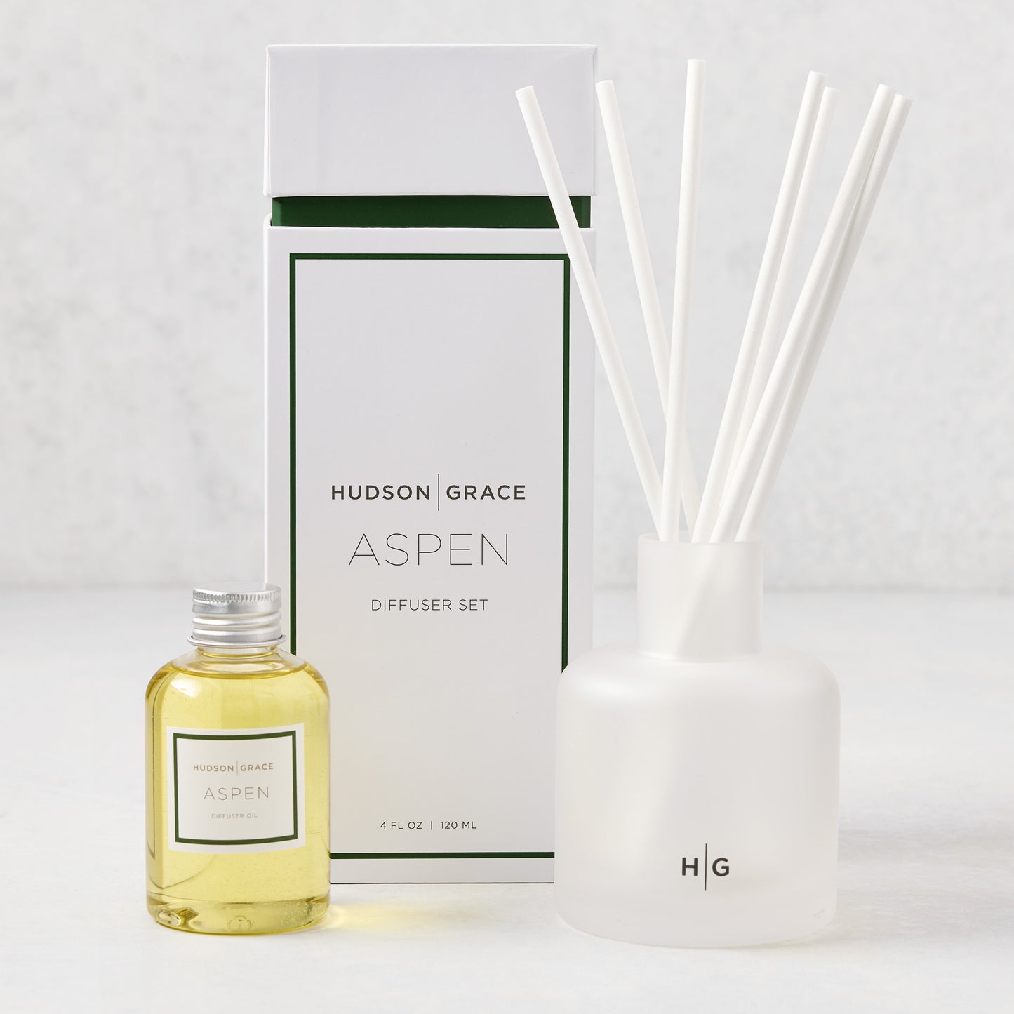 Hudson Grace Aspen Scented Reed Diffuser set: frosted white glass vessel, 6 white reeds, oil bottle, and white box.