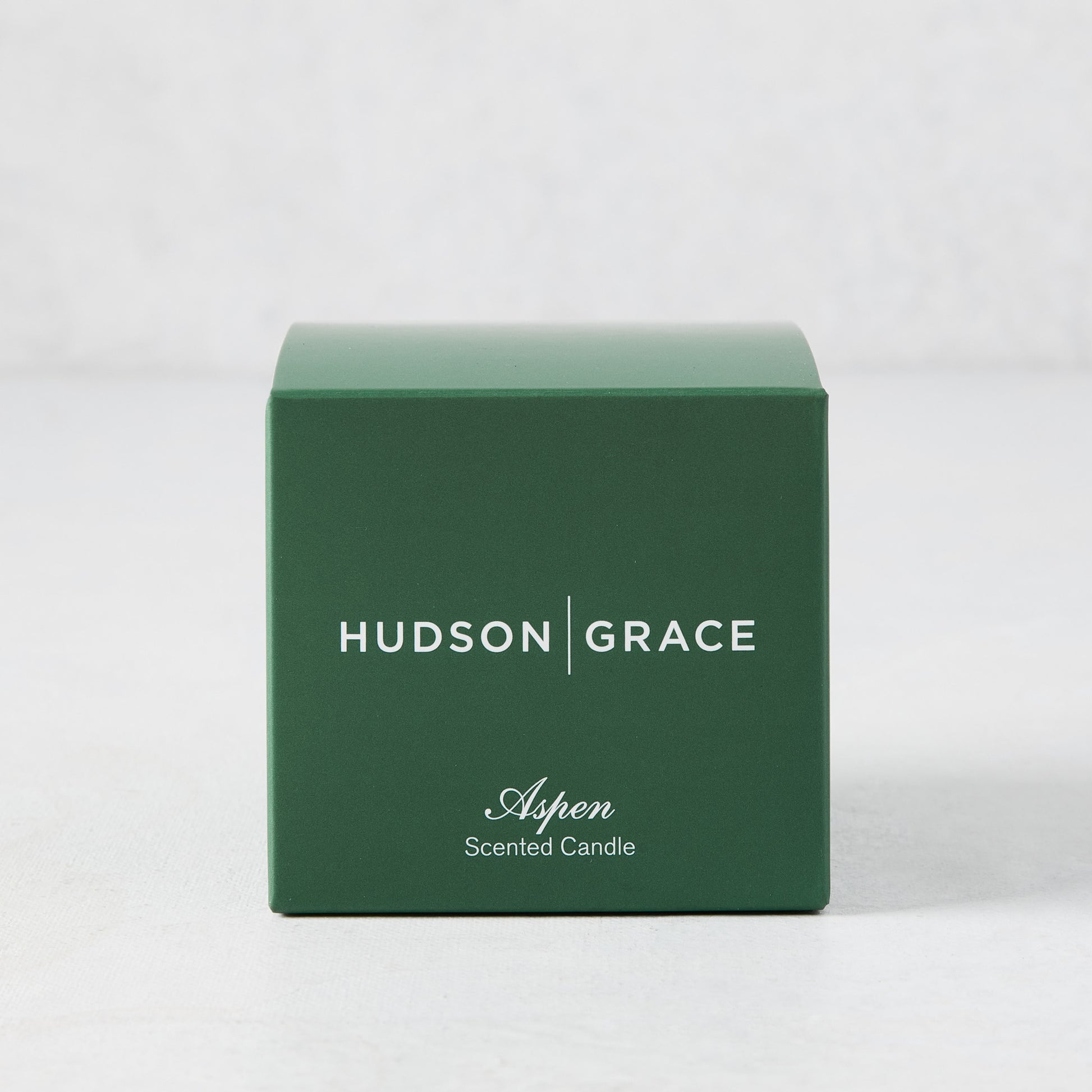 Hudson Grace Aspen Scented Votive candle in a dark green box with white text.