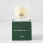 Hudson Grace Aspen Scented Votive candle in a frosted glass vessel, lit, on a dark green gift box.
