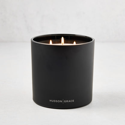 Hudson Grace Bleecker Scented 3-Wick Candle in a matte black heavyweight glass vessel, lit.