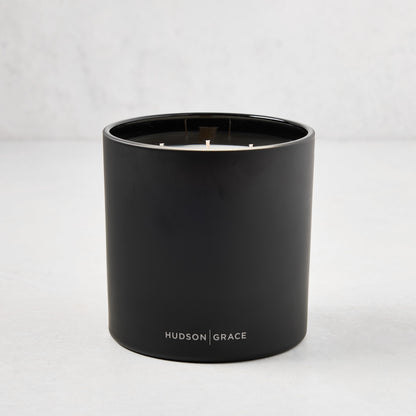 Hudson Grace Bleecker 3-wick candle in a matte black heavyweight glass vessel with white text logo.