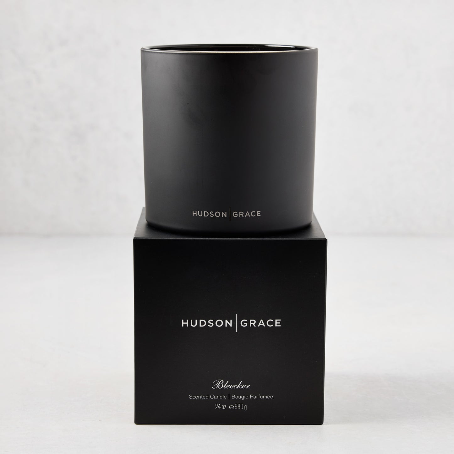 Hudson Grace Bleecker Scented 3-Wick Candle in a matte black glass vessel on its matching black gift box.