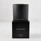 Hudson Grace Bleecker Scented 3-Wick Candle in a matte black glass vessel on its matching black gift box.