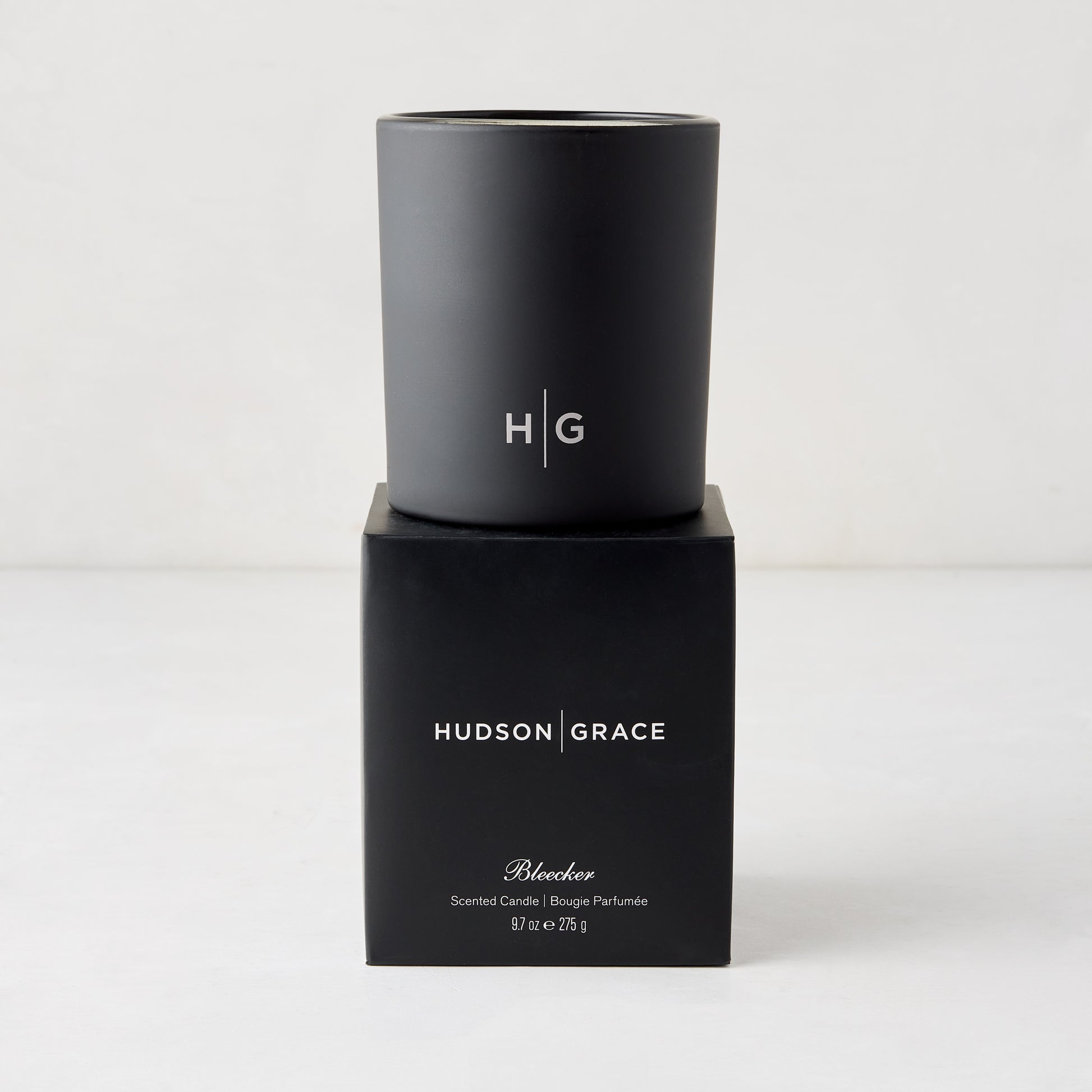 Hudson Grace Bleecker Scented Candle, black matte glass vessel with HG logo, on its black box.