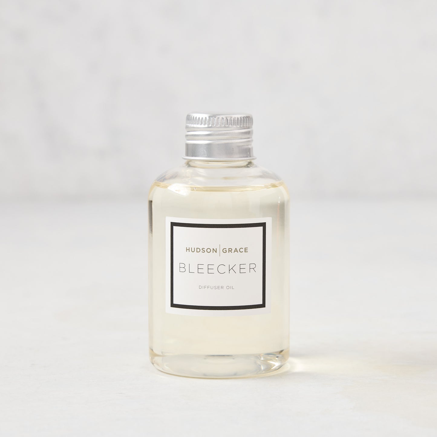 Hudson Grace Bleecker Scented Reed Diffuser Oil Refill, clear glass bottle with silver cap and white label.