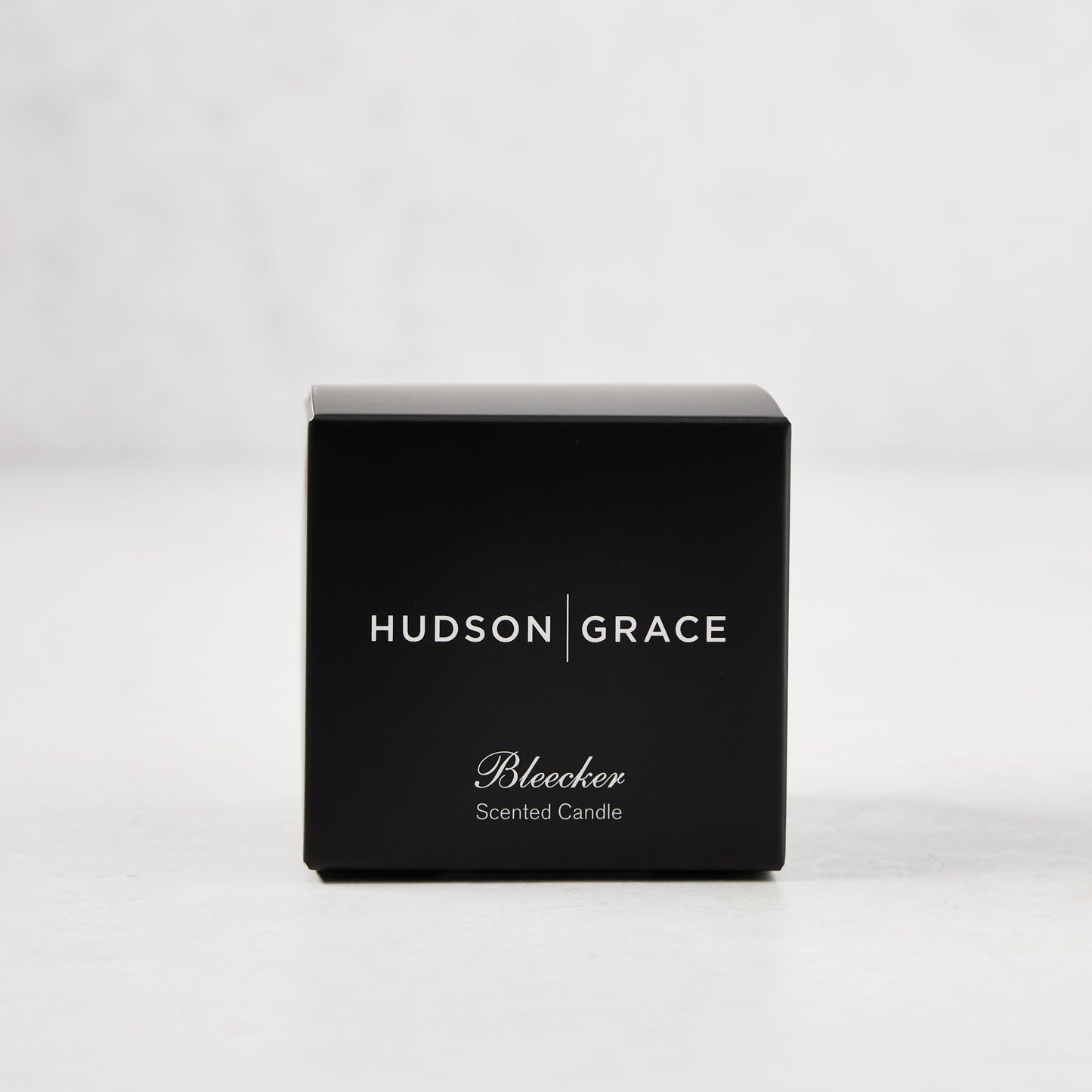 Hudson Grace Bleecker Scented Votive in a black box with white text, on a light background.