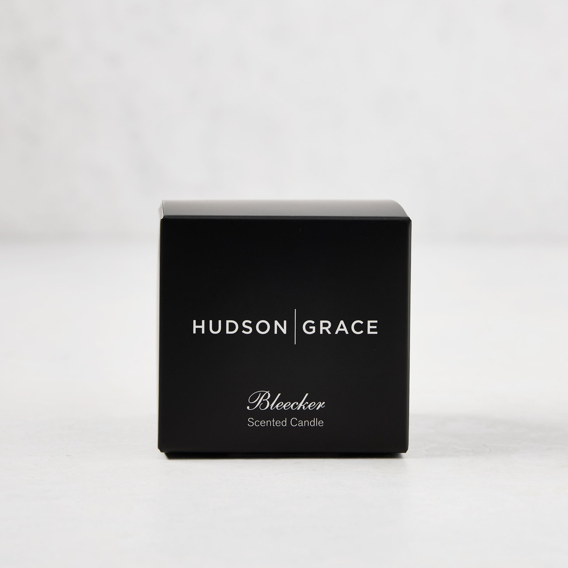 Hudson Grace Bleecker Scented Votive in a black box with white text, on a light background.