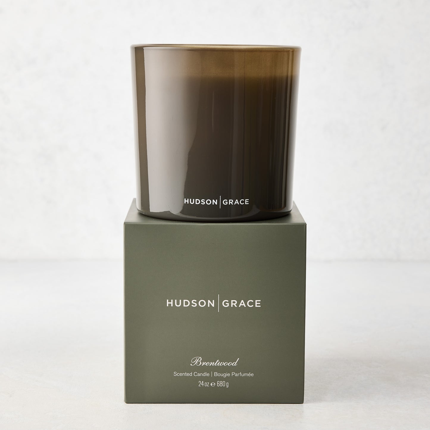 Hudson Grace Brentwood 3-Wick Candle in a dark glass vessel, on its olive green gift box.