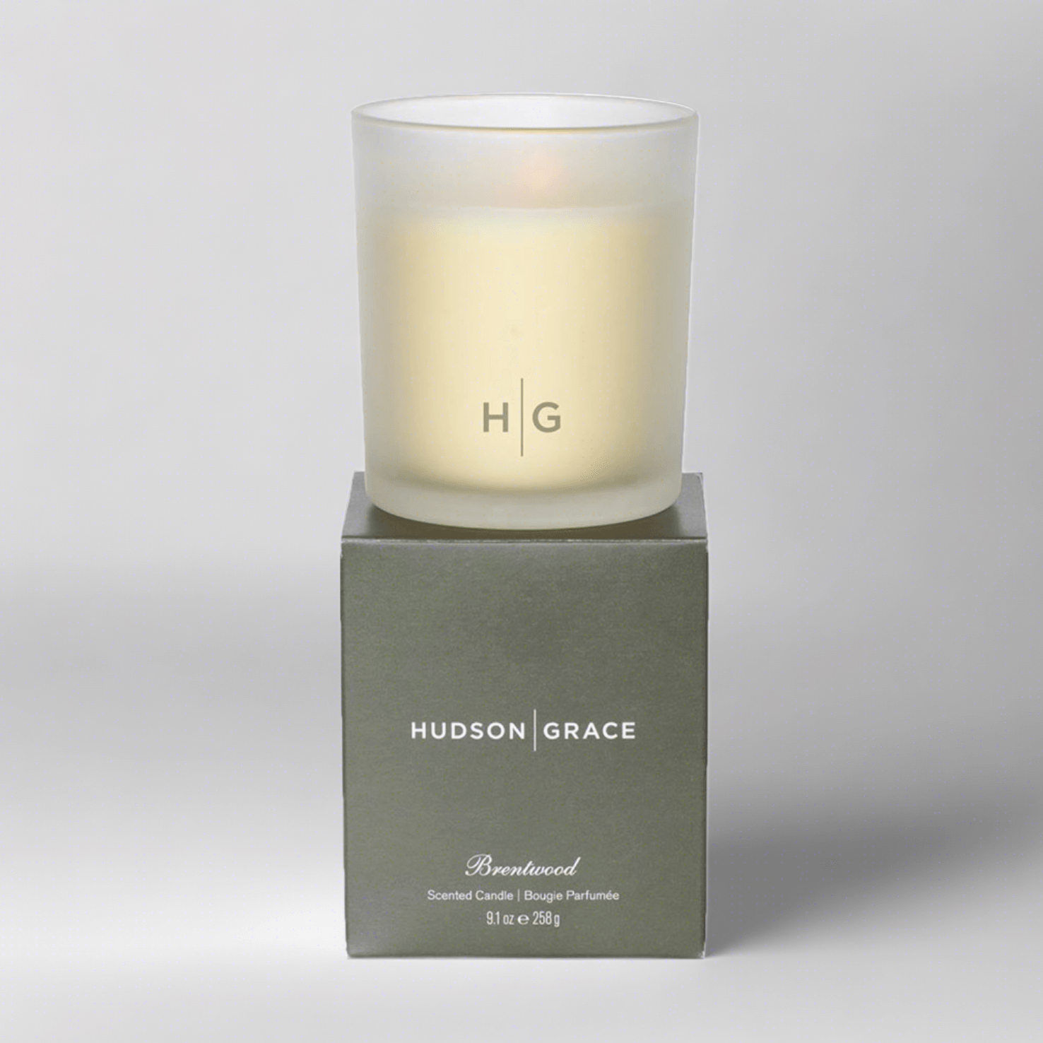 Hudson Grace Brentwood scented candle in a frosted glass vessel with HG logo, on its olive green box.