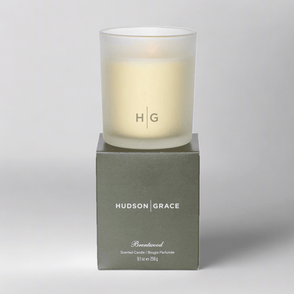 Hudson Grace Brentwood scented candle in a frosted glass vessel with HG logo, on its olive green box.