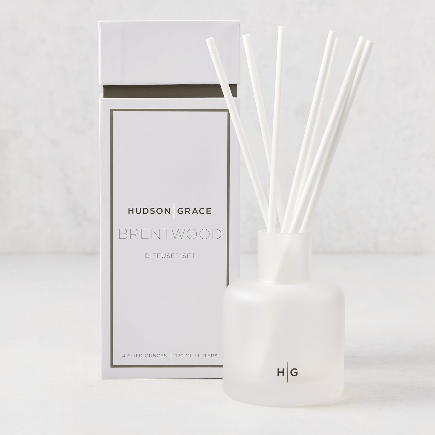 Hudson Grace Brentwood scented reed diffuser set with frosted glass vessel, white reeds, and white box.