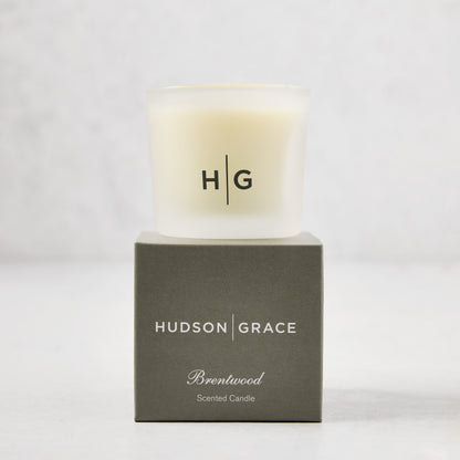 Hudson Grace Brentwood Votive Scented Candle in a frosted glass vessel on its gray gift box.