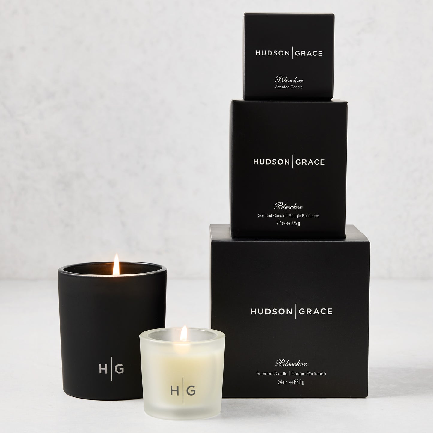 Hudson Grace Bleecker Candle Gift Set: three black boxes stacked, two lit candles in black and frosted glass.