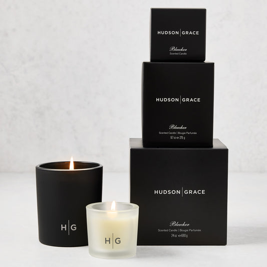 Hudson Grace Bleecker Candle Gift Set: three black boxes stacked, two lit candles in black and frosted glass.