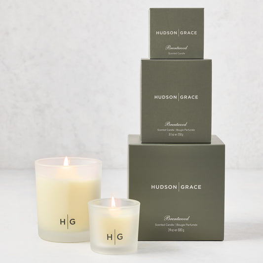 Hudson Grace Brentwood Candle Gift Set: 3 frosted glass candles and 3 stacked olive green boxes.