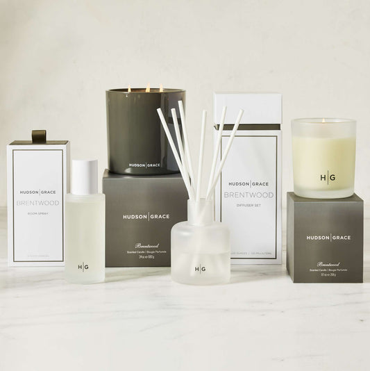 Hudson Grace Brentwood scent collection: room spray, diffuser, and candles in white and dark gray packaging.