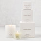Hudson Grace Greenwich Candle Gift Set: 3 white boxes stacked, 2 lit candles (votive, classic) with HG logo.