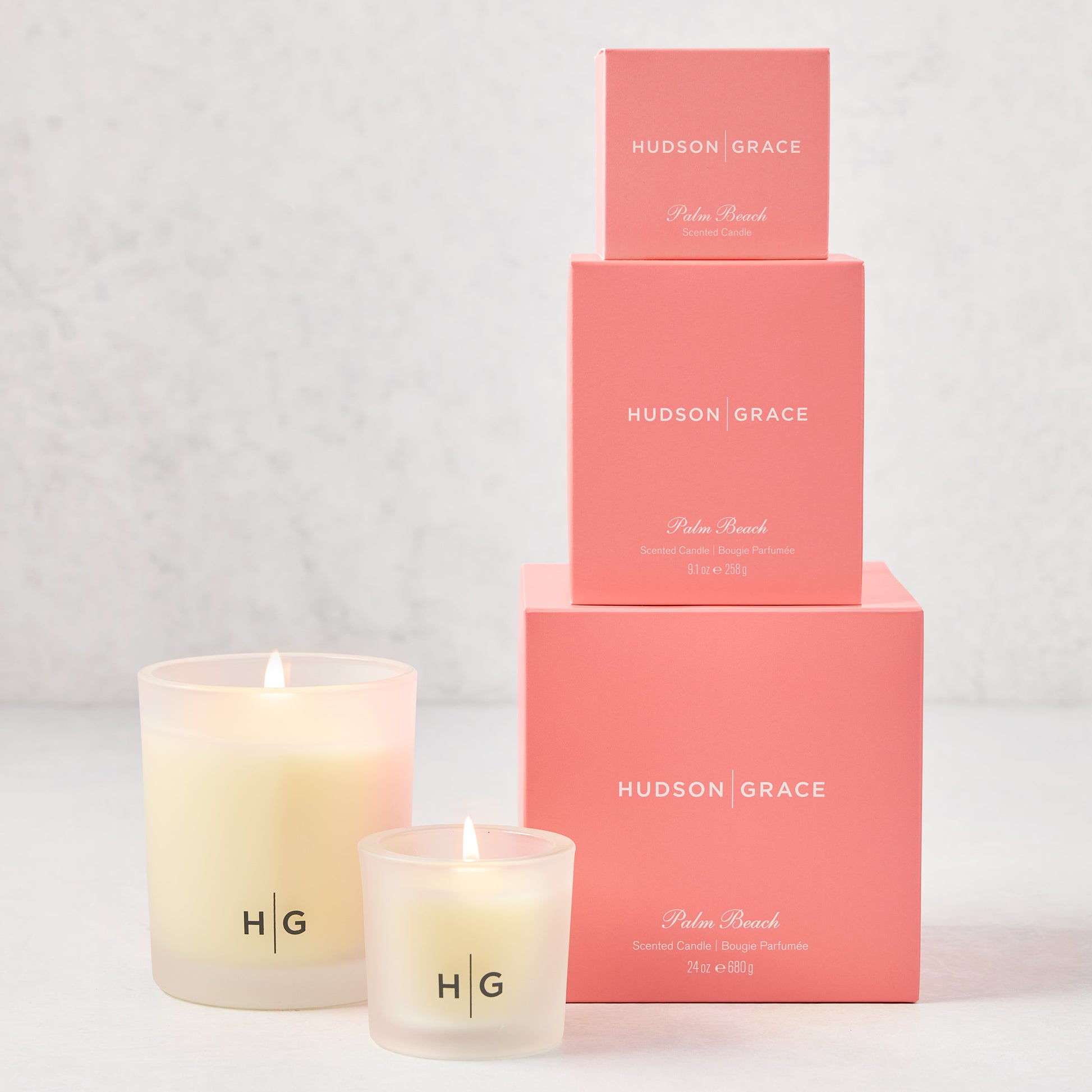 Hudson Grace Palm Beach candle gift set: three frosted glass candles with HG logo, three stacked coral pink boxes.