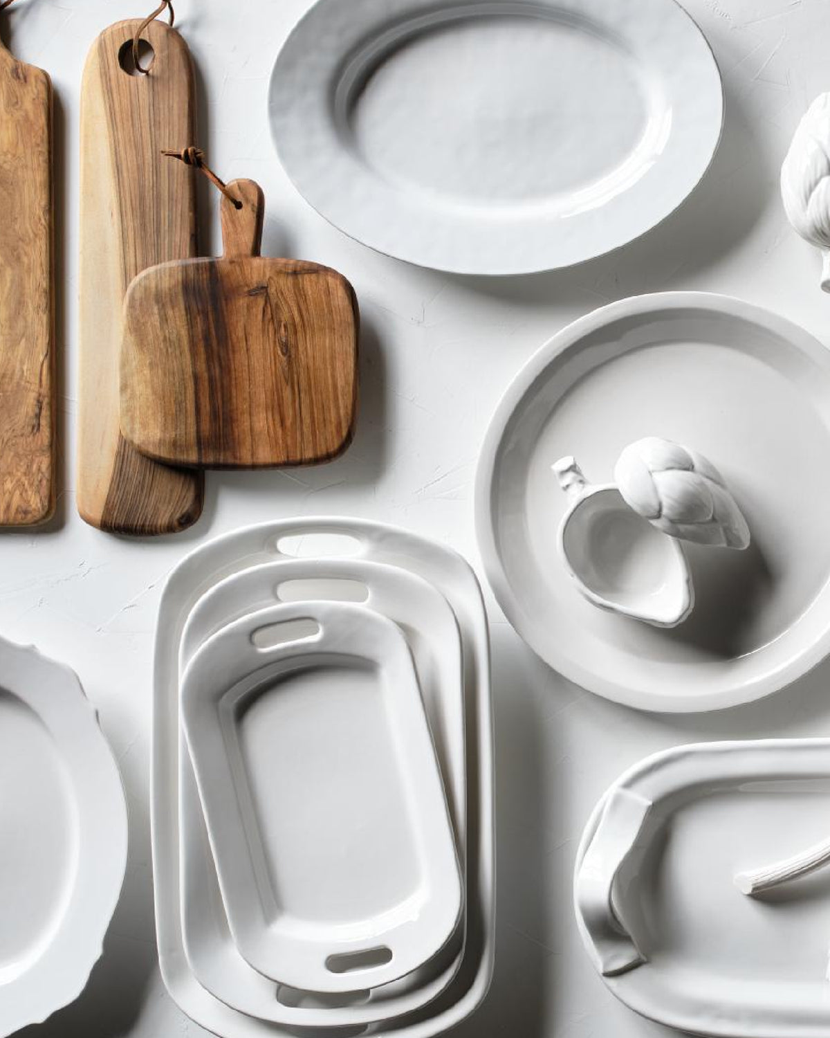 Hudson Grace European-made white serving platters displayed with wood serving boards and ceramic artichokes