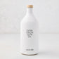 Hudson Grace Extra Virgin Olive Oil in a white ceramic bottle with a wood cork and black label.