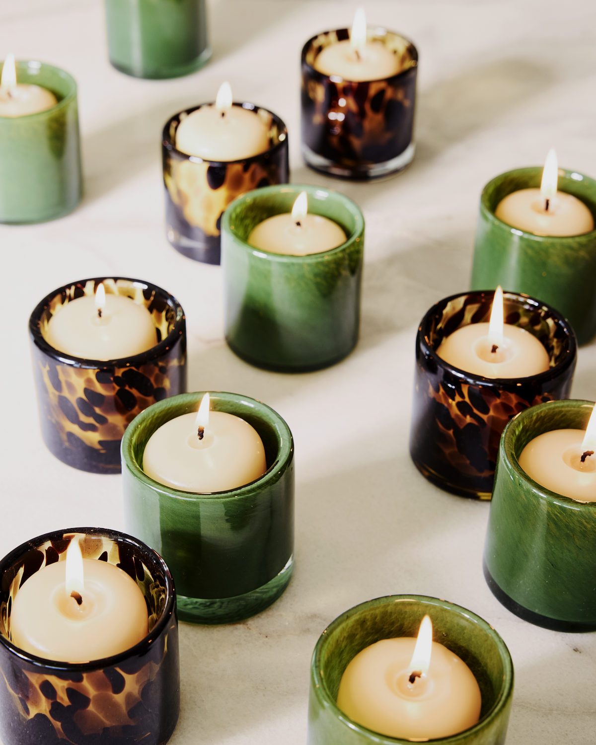 Hudson Grace green and tortoise glass votive holders with lit unscented amber votive candles