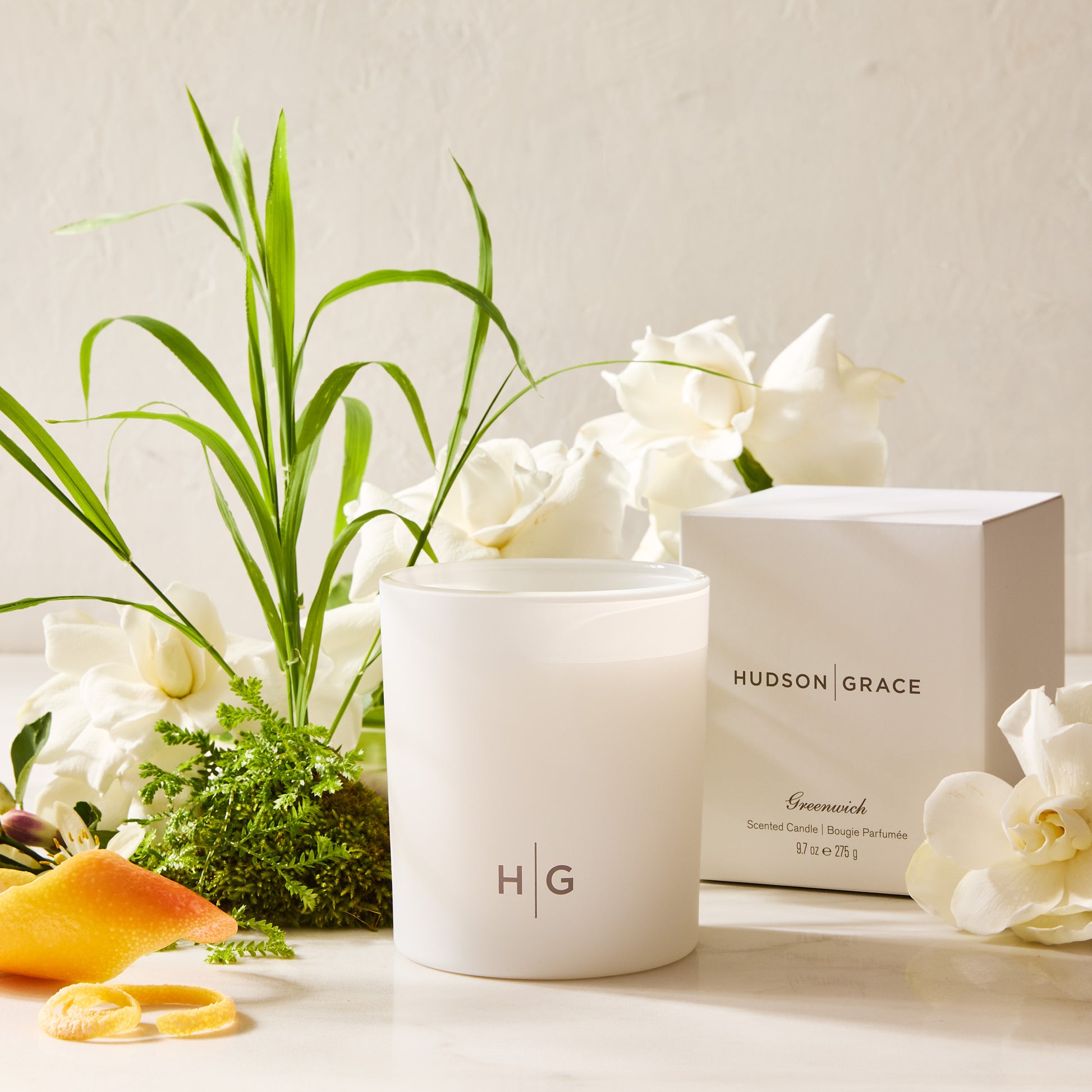 Hudson Grace Greenwich 3-wick candle in a white frosted glass vessel with HG logo, white box, and gardenias.
