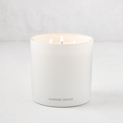 Hudson Grace Greenwich 3-wick candle in a white matte glass vessel with "HUDSON GRACE" logo.