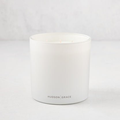 Hudson Grace Greenwich 3-wick candle in a white matte glass vessel with light pink wicks.