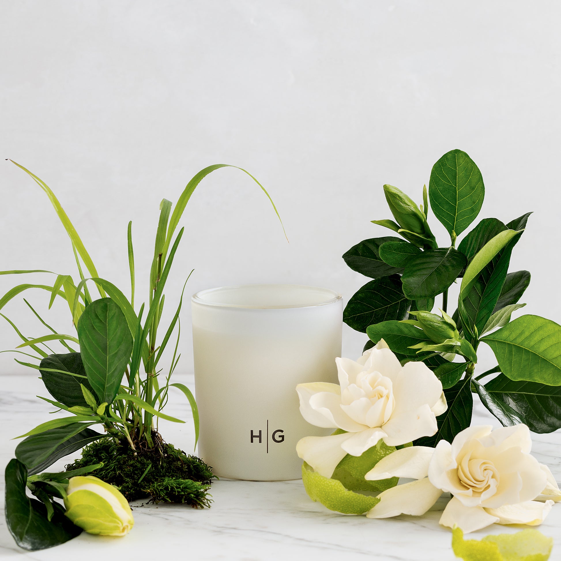 Hudson Grace Greenwich 3-wick scented candle in a white glass vessel with gardenia, grass, and lime peel.