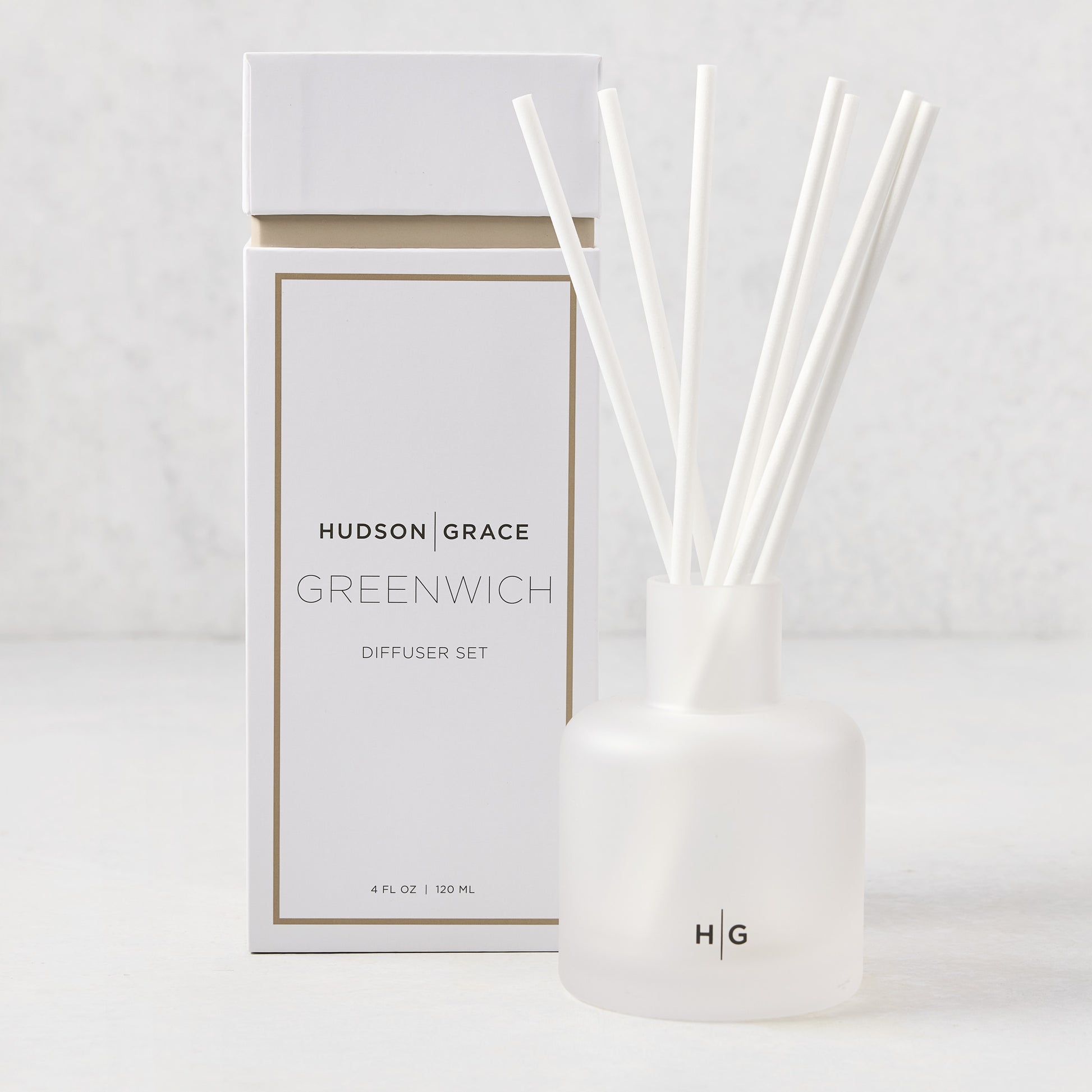 Hudson Grace Greenwich scented reed diffuser set: frosted white glass vessel with HG logo, 6 white fiber reeds, and white box.