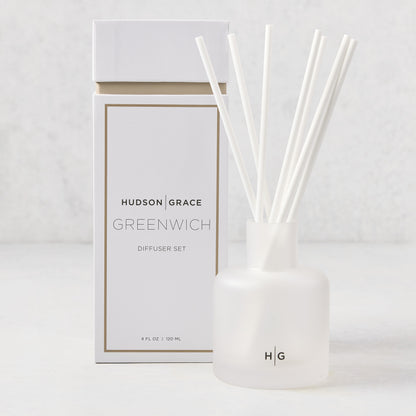 Hudson Grace Greenwich scented reed diffuser set: frosted white glass vessel with HG logo, 6 white fiber reeds, and white box.
