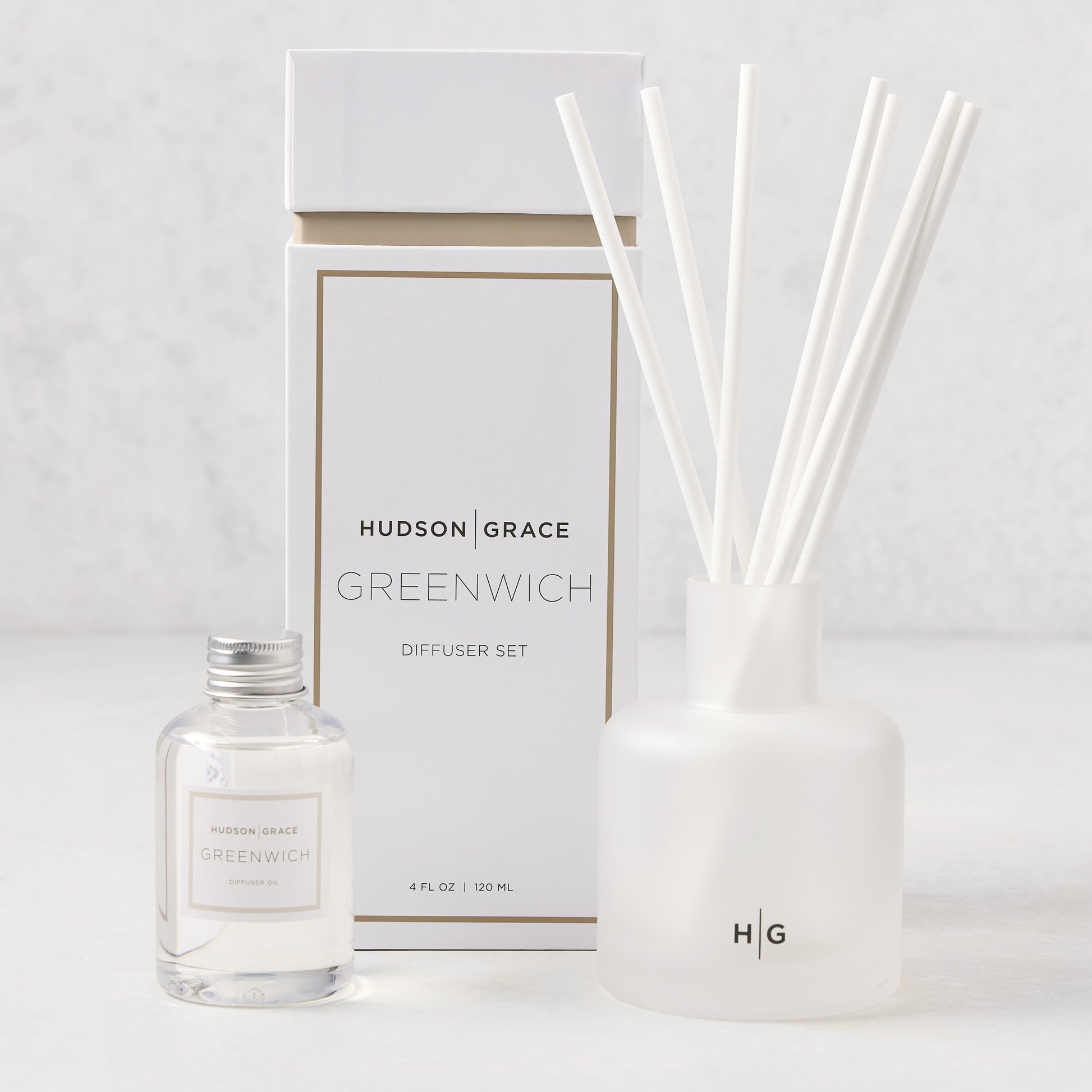 Hudson Grace Greenwich Scented Reed Diffuser set with frosted glass vessel, 6 white reeds, and 4 fl oz oil bottle.
