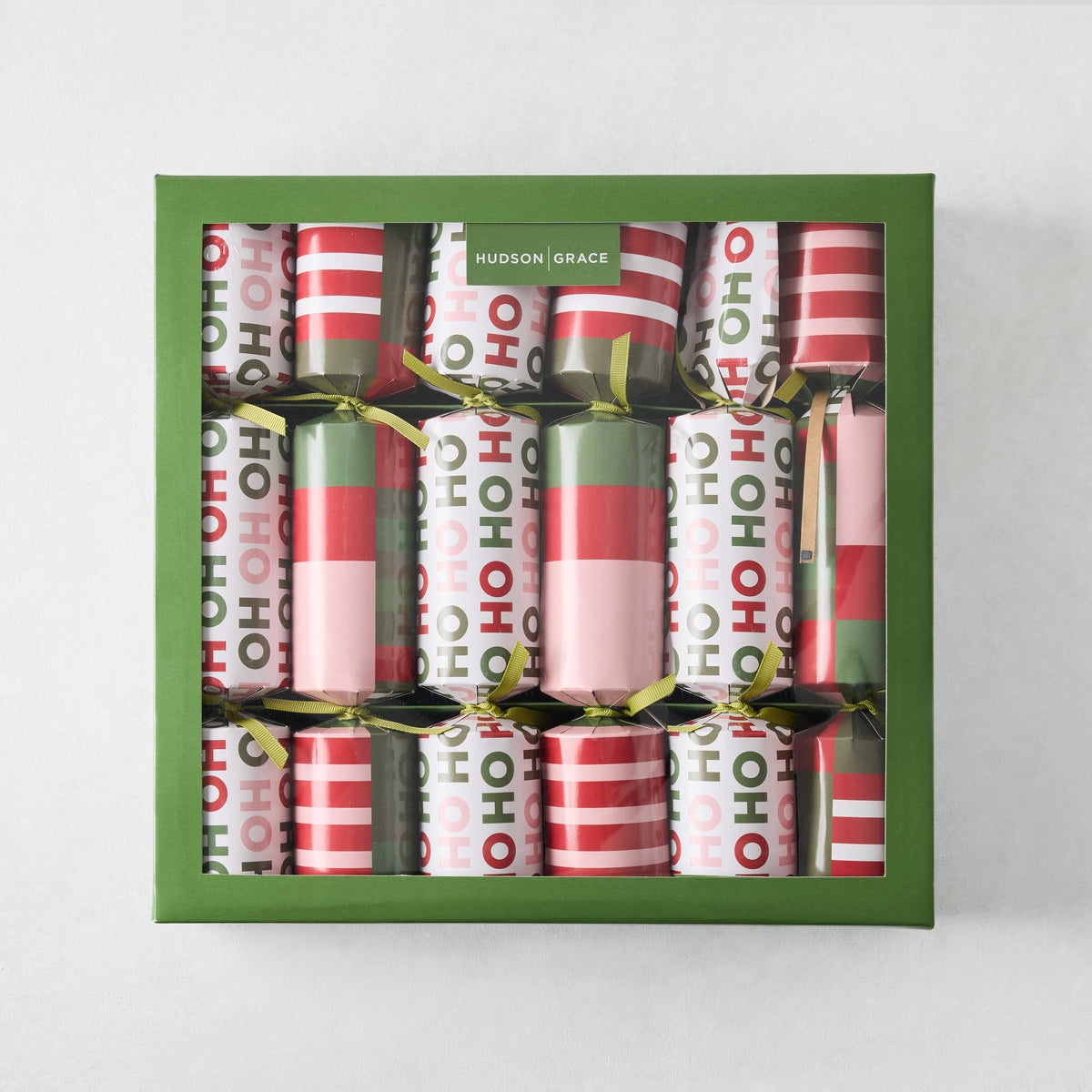 Set of six holiday crackers in a green box, featuring red, pink, and green striped and Ho Ho Ho patterned paper wrappers.