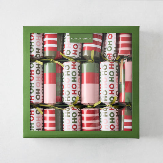 Set of six holiday crackers in a green box, featuring red, pink, and green striped and Ho Ho Ho patterned paper wrappers.