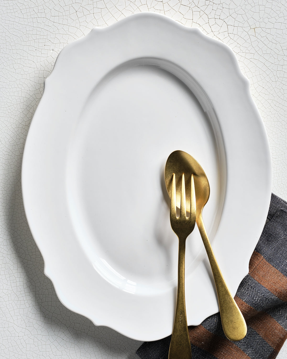 Hudson Grace Modern Lungarno white oval serving platter with scalloped edges and brass serving utensils