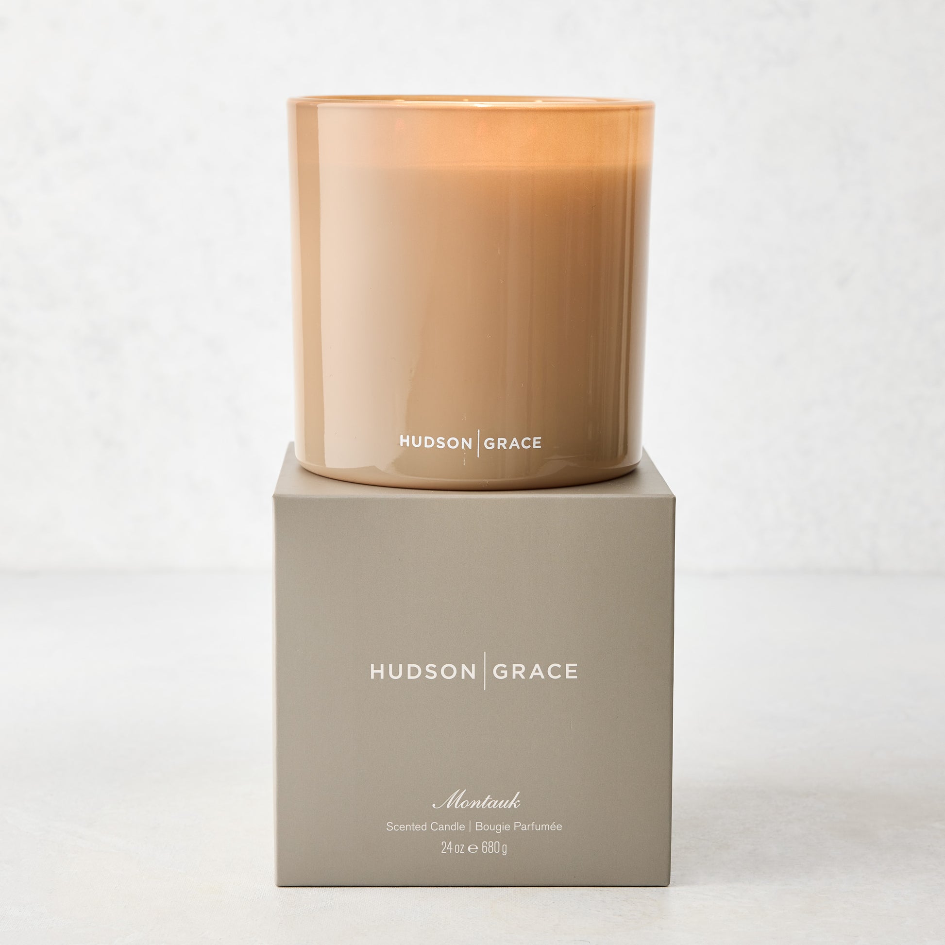 Hudson Grace Montauk 3-wick scented candle in a translucent amber glass vessel, on its gray gift box.