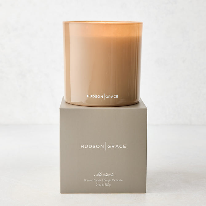 Hudson Grace Montauk 3-wick scented candle in a translucent amber glass vessel, on its gray gift box.
