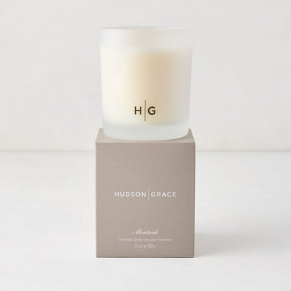 Hudson Grace Montauk Scented Candle in a frosted glass vessel with HG logo, on a matching beige box.