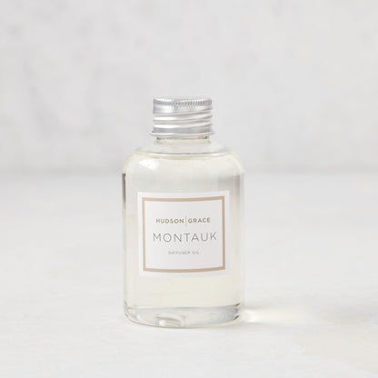 Hudson Grace Montauk scented reed diffuser oil refill, clear glass bottle with silver cap and white label.