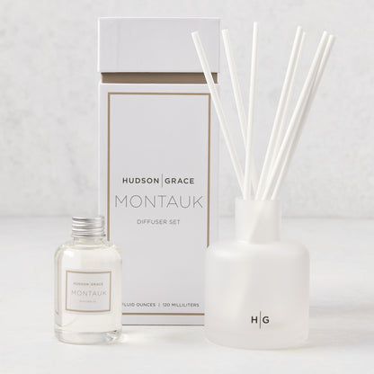 Hudson Grace Montauk Scented Reed Diffuser set: clear glass bottle, frosted glass vessel with white reeds, and white box.